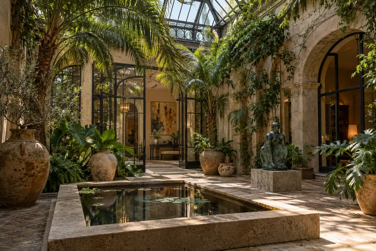Patio sous verrière, bassin de pierre, palmiers et sculpture de bronze.